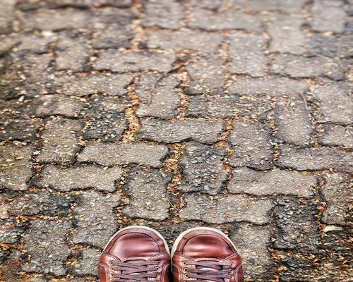 A pair of comfortable walking shoes on a brick paved pathway during an early evening stroll