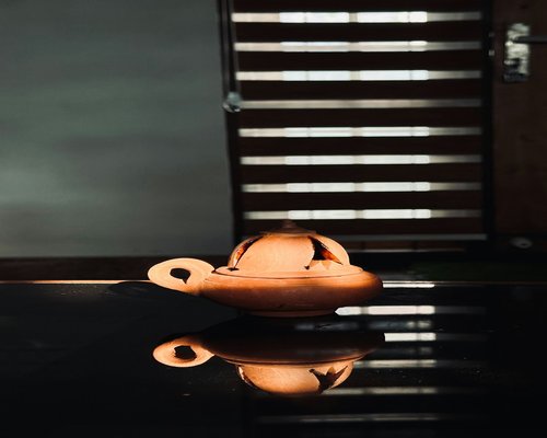 A warm domestic evening setting with a clay lamp lit beautifully inside a calm traditional Indian living room