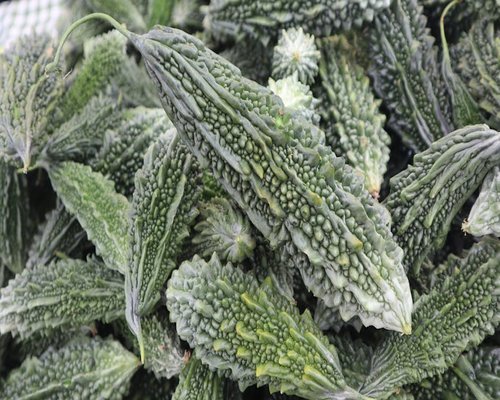 A close up shot of fresh local green vegetables like spinach and bitter gourd at a local Indian market stall