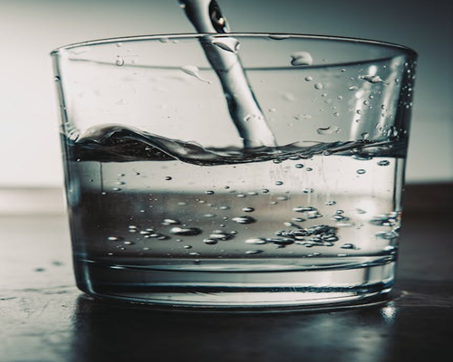 Pure clean water being poured gently into a steel container during a hot summer day in India
